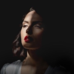 Portrait féminin en clair-obscur, visage éclairé sur fond noir