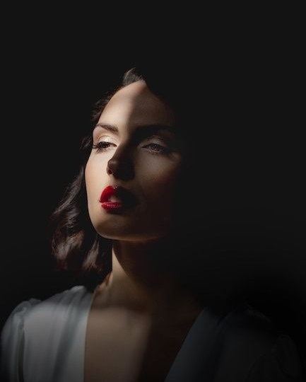 Portrait féminin en clair-obscur, visage éclairé sur fond noir