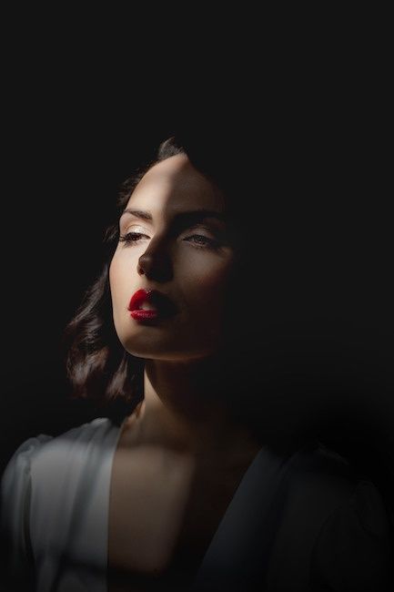 Portrait féminin en clair-obscur, visage éclairé sur fond noir