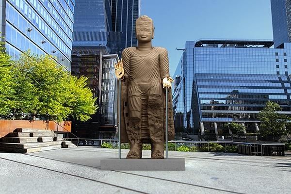 Sculpture monumentale dorée installée sur une place entre des gratte-ciel